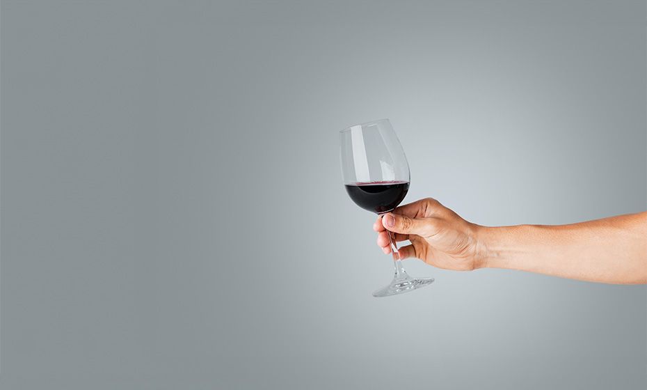 A hand holding a glass of red wine representing the fine dinning industry