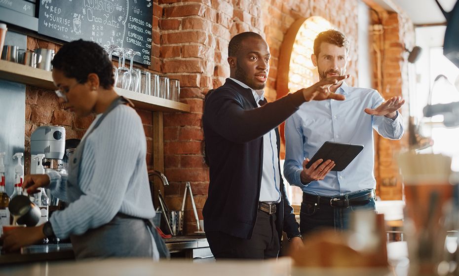 Restaurant owner holding pos system talking to customer