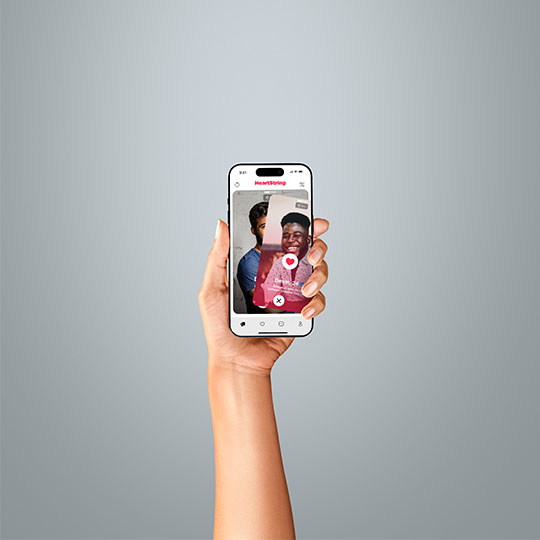 A hand holding an iPhone with a dating app on the screen representing the online dating industry