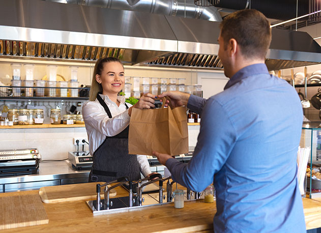 A woman at a cafe counter handing a man a bag