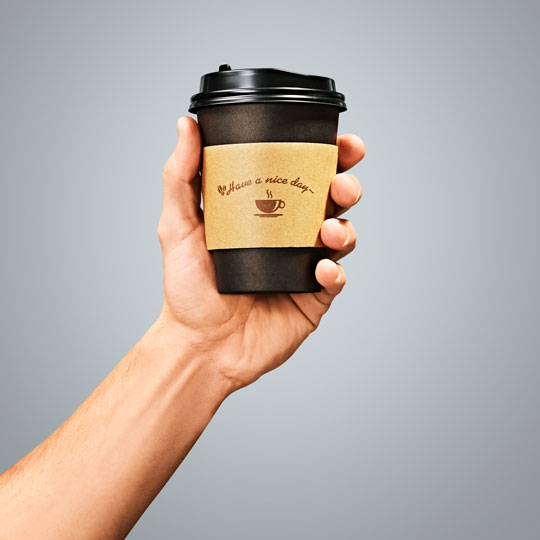 A hand holding a cup of coffee representing the convenience retail industry