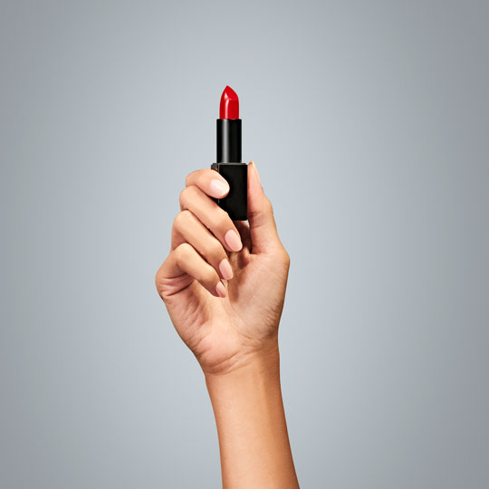 A hand holding lipstick representing the beauty industry