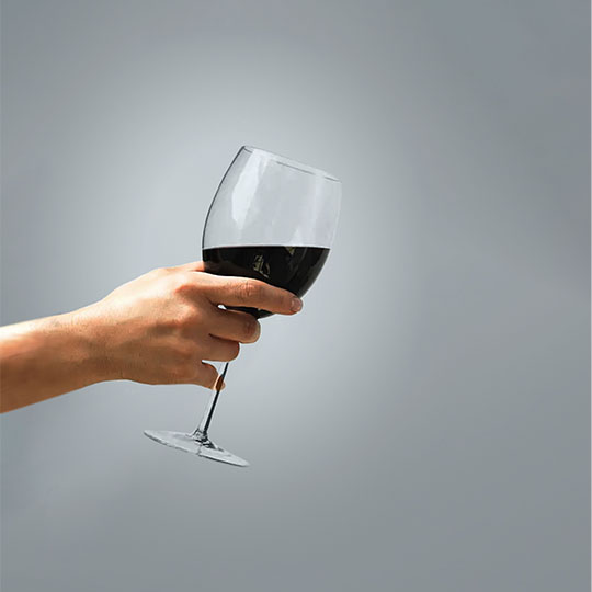 A hand holding a glass of red wine representing the fine dinning industry